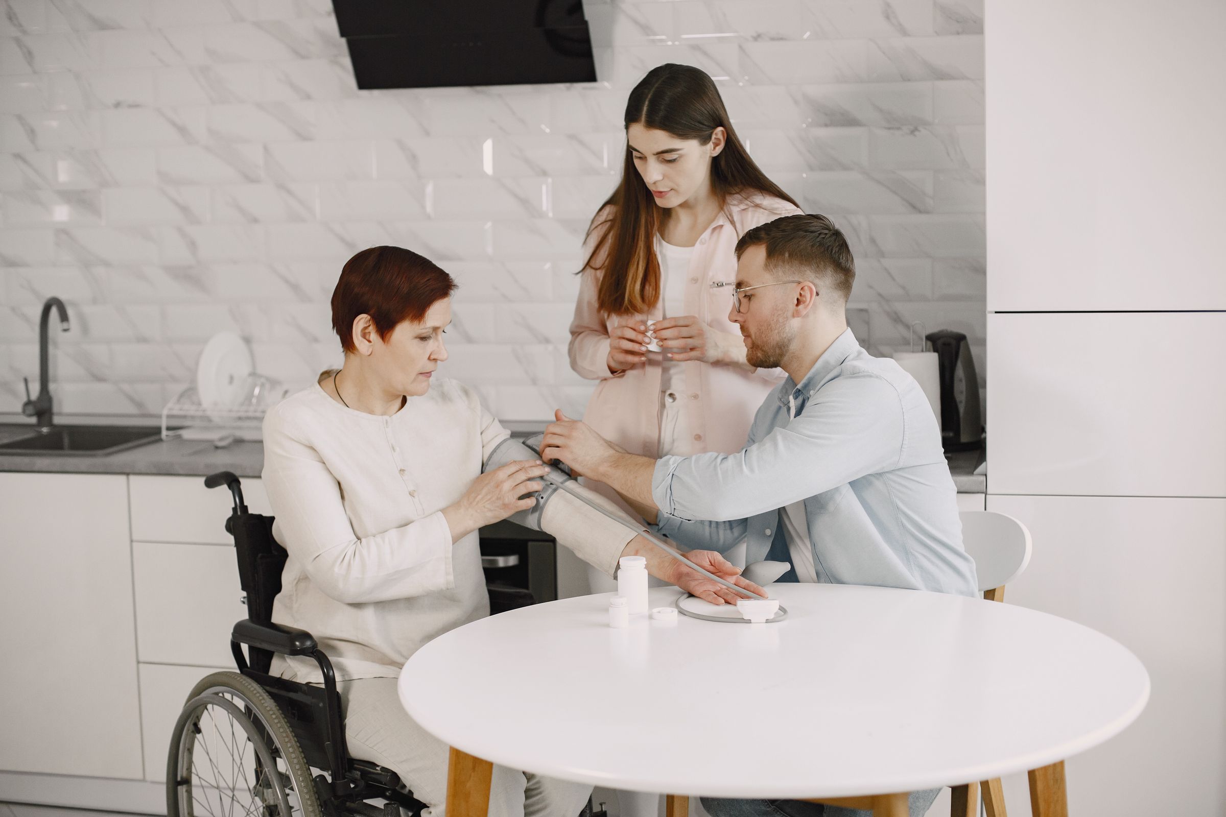 A clinician taking a blood pressure reading at a kitchen table during a home visit